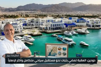 صورة لرجل مبتسم يقف أمام ميناء مرسى زايد في العقبة بالأردن مع قوارب ومباني بيضاء.