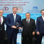 ممثلو البنك الأردني الكويتي يحملون درع التكريم في مؤتمر دعم الاستثمار في سوريا بحضور مسؤولين.