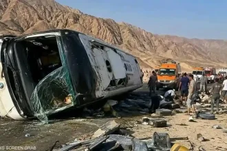 حافلة ركاب بيضاء منقلبة على جانبها في منطقة جبلية بطريق دهب نويبع بوجود سيارات الإسعاف