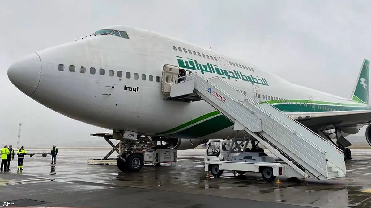 طائرة الخطوط الجوية العراقية تجثم على أرض المطار متصلة بسلم الركاب وسط أجواء غائمة.