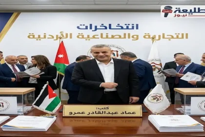 صورة لـ عماد عبدالقادر عمرو ببدلة سوداء يقف أمام طاولة عليها لوحة باسمه وأعلام أردنية وصناديق اقتراع، خلف خلفية مكتوب عليها "انتخابات الغرف التجارية والصناعية الأردنية" وشعار "الطليعة نيوز".