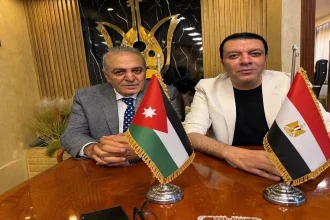 هاني الجراح ومصطفى كامل خلال توقيع بروتوكول تعاون فني بين الأردن ومصر وأمامهما علما البلدين.