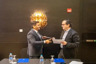 لحظة توقيع اتفاقية شراكة وتبادل المستندات بين رجلين في قاعة اجتماعات رسمية.