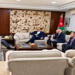 جانب من عقد لقاء حجازين مع مسؤولين في مكتب رسمي يضم العلم الأردني ولوحة فسيفساء أثرية.