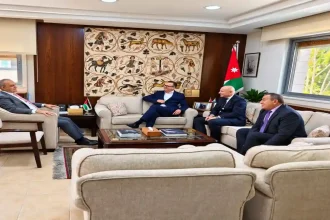 جانب من عقد لقاء حجازين مع مسؤولين في مكتب رسمي يضم العلم الأردني ولوحة فسيفساء أثرية.