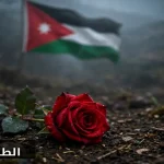 وردة حمراء على تراب مبلل ترمز للدماء الزكية وشهداء الوطن وعلم الأردن يرفرف خلفها بحزن وشموخ كبير