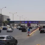 سيارات تسير في طريق عمان الرئيسي بالقرب من جسر المشاة واللوحات الإعلانية في الأردن