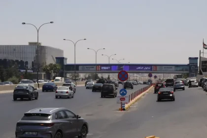 سيارات تسير في طريق عمان الرئيسي بالقرب من جسر المشاة واللوحات الإعلانية في الأردن