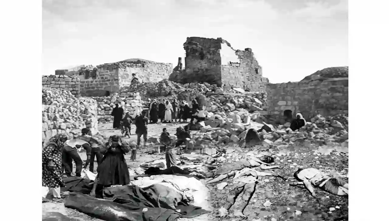 مجزرة قرية قبية 1953 صورة تاريخية لجثامين الشهداء على الأرض ومنازل مدمرة ونساء فلسطينيات يبكين